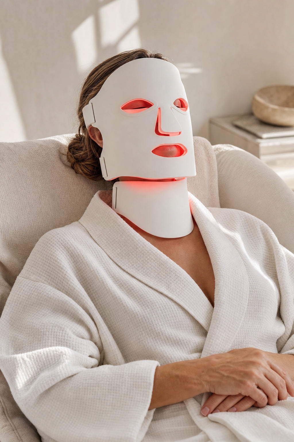 Woman relaxing while wearing the Redermis LED light therapy mask and neck panel [white]