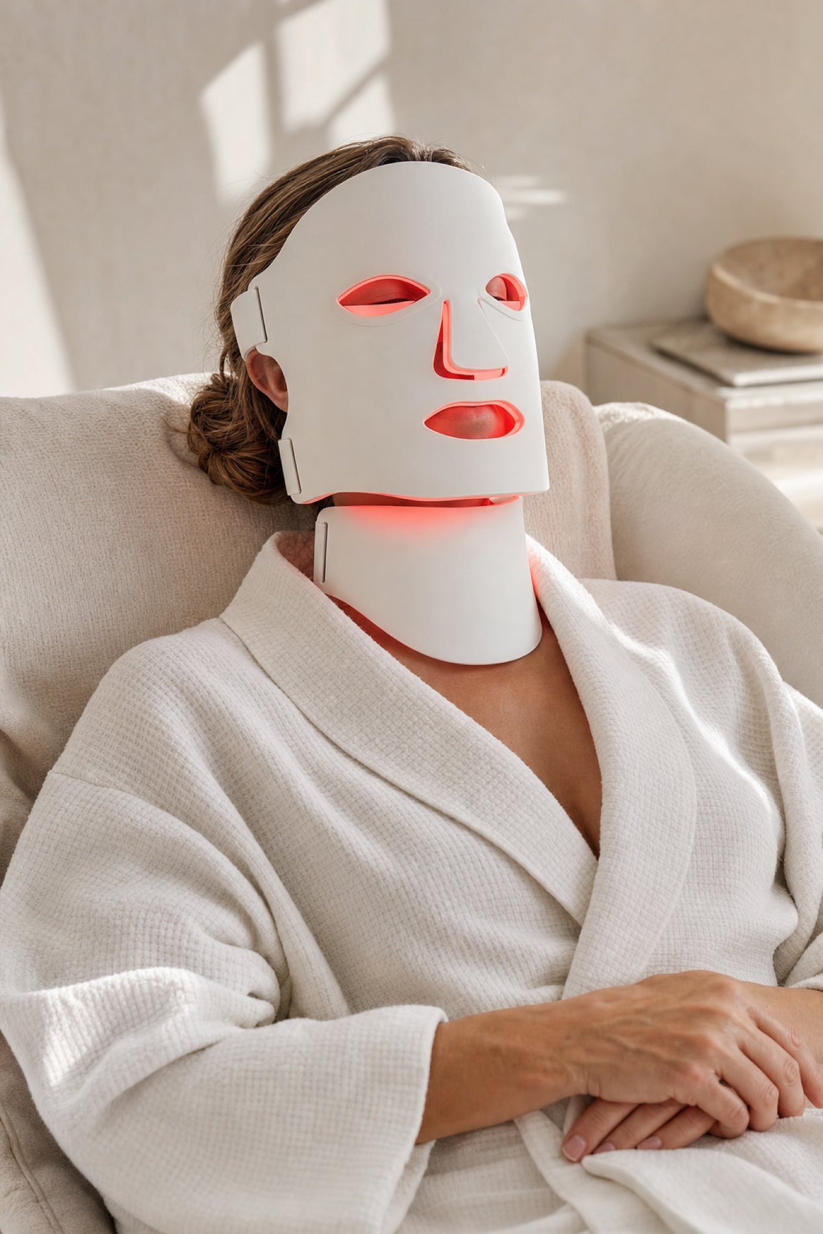 Woman relaxing while wearing the Redermis LED light therapy mask and neck panel [white]